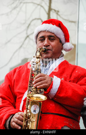 Man dressed in a Santa outfit playing the saxophone Stock Photo