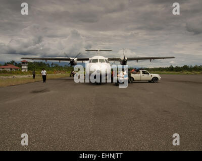 Dekai, Indonesia - January 12, 2015:  Aircraft being unloaded by local airline ground services staff Stock Photo