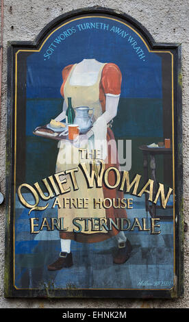 Amusing inn sign of The Quiet Woman in Earl Sterndale in the Derbyshire White Peak showing a headless woman with food and beer Stock Photo