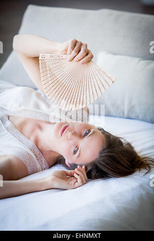 Woman cooling her face with a fan. Stock Photo