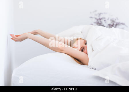 Woman waking up and stretching in bed.