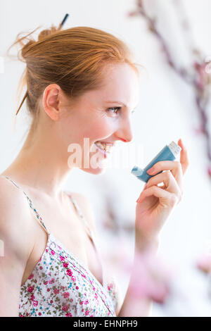 Woman using an aerosol inhaler that contains bronchodilator for the treatment of asthma. Stock Photo