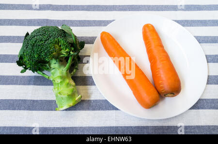 Two Carrots on White Plate with Green Broccoli on Blue and White Background Stock Photo