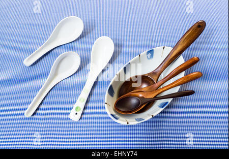 Set of Wooden Spoon in White Bowl with Three Ceramic Spoon on Blue Background Stock Photo