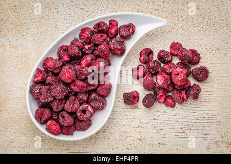 Freeze dried cherries in a teardrop bowl against rustic barn wood. Stock Photo