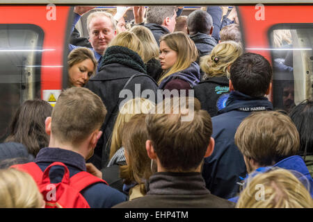London, UK. 16th March, 2015. Passengers await packed Northern Line trains at Stockwell station. They are bombarded by announcements that all lines have a good service and are faced by a helpful sign, put up by TFL, telling them not to crowd around one door. Unfortunately they are forced by weight of numbers to stand perilously close to the platform edge.  Stockwell Station on the Northern Line, London Unerground, 16 Mar 2015. Credit:  Guy Bell/Alamy Live News Stock Photo