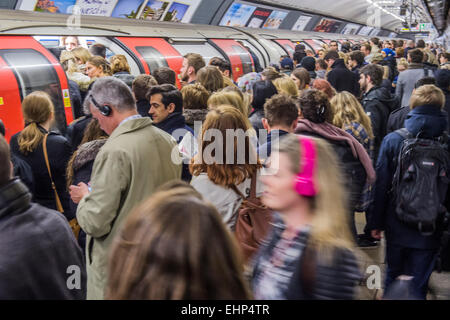 London, UK. 16th March, 2015. Passengers await packed Northern Line trains at Stockwell station. They are bombarded by announcements that all lines have a good service and are faced by a helpful sign, put up by TFL, telling them not to crowd around one door. Unfortunately they are forced by weight of numbers to stand perilously close to the platform edge.  Stockwell Station on the Northern Line, London Unerground, 16 Mar 2015. Credit:  Guy Bell/Alamy Live News Stock Photo