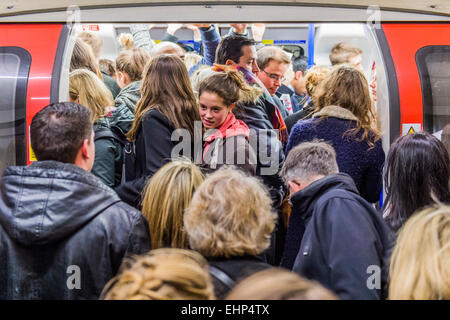 London, UK. 16th March, 2015. Passengers await packed Northern Line trains at Stockwell station. They are bombarded by announcements that all lines have a good service and are faced by a helpful sign, put up by TFL, telling them not to crowd around one door. Unfortunately they are forced by weight of numbers to stand perilously close to the platform edge.  Stockwell Station on the Northern Line, London Unerground, 16 Mar 2015. Credit:  Guy Bell/Alamy Live News Stock Photo