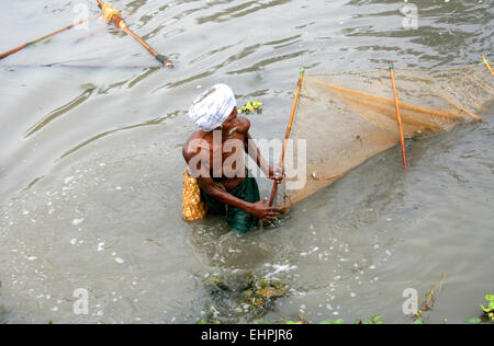 fisherman spread the net in a traditional way to catch fish in irrigation canal water on February 15,2012 in Nandivada,AP,India. Stock Photo