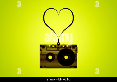 A cassette tape on a lime green back-lit background with tape coming out of the cassette to form a heart shape. Stock Photo