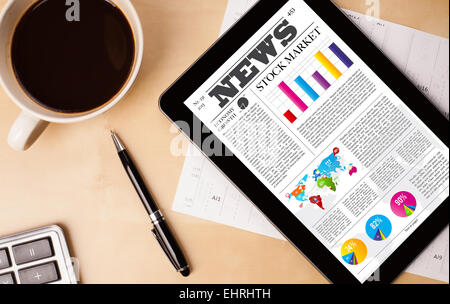 Tablet pc shows news on screen with a cup of coffee on a desk Stock Photo
