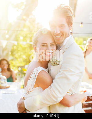 Portrait of young couple embracing in garden during wedding reception Stock Photo