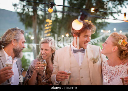 Young couple and their guests with champagne flutes during wedding reception in garden Stock Photo