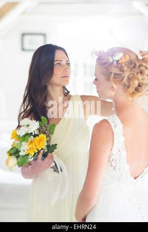 Bridesmaid helping bride with hairstyle in bedroom Stock Photo