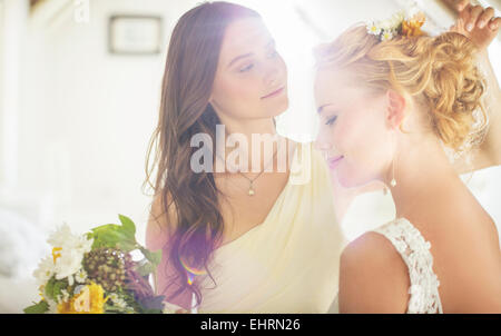 Bridesmaid helping bride with hairstyle in bedroom Stock Photo