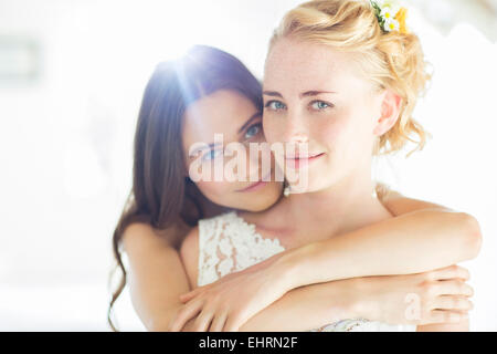 Portrait of bridesmaid embracing bride in bedroom Stock Photo
