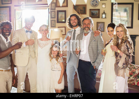 Portrait of young couple with guests and champagne flutes at wedding reception Stock Photo
