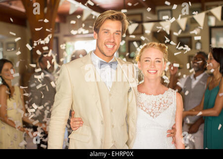 Portrait of smiling young couple standing in falling confetti during wedding reception Stock Photo