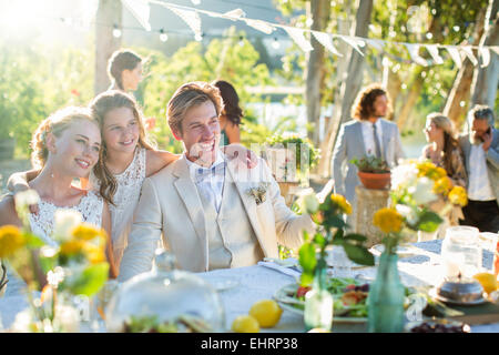 Young couple and bridesmaid during wedding reception in domestic garden Stock Photo