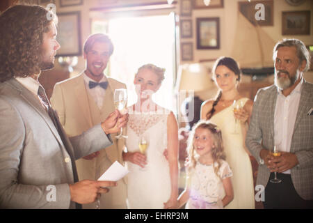 Best man toasting with champagne and giving speech during wedding reception in domestic room Stock Photo