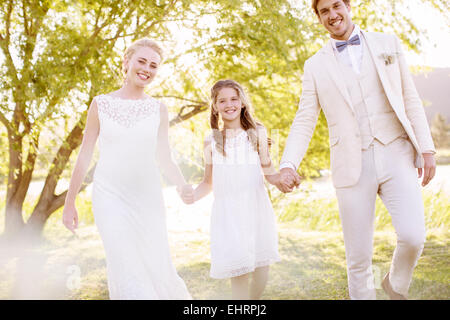 Bride, bridegroom and bridesmaid walking in domestic garden Stock Photo