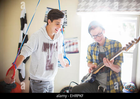 Two teenage boys having fun and playing electric guitar in room Stock Photo