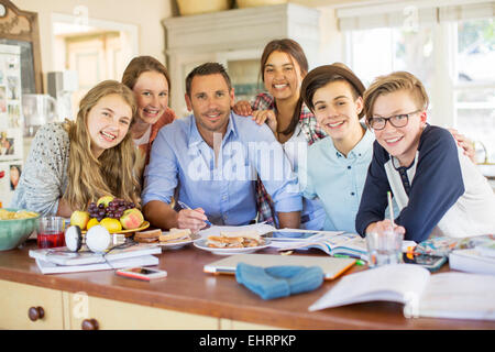 Group of teenagers with mid adult man sitting at table in dining room Stock Photo
