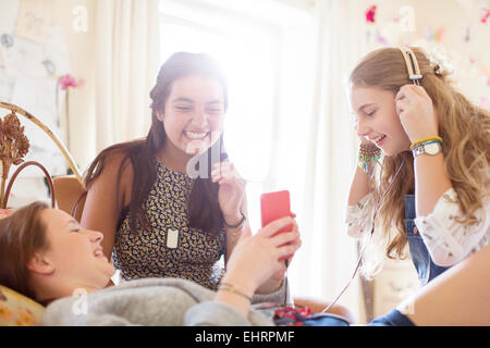 Three teenage girls listening to music on bed in bedroom Stock Photo