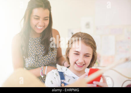 Two teenage girls sharing smartphone and smiling Stock Photo