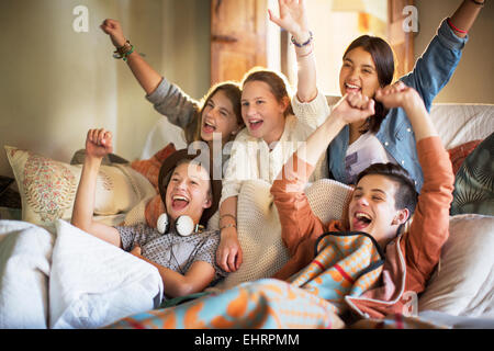 Group of teenagers having fun while watching tv on sofa Stock Photo