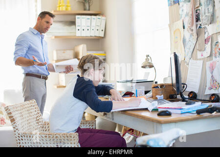 Father helping teenage son doing his homework in room Stock Photo