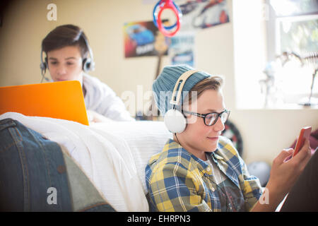 Two teenage boys using electronic devices in room Stock Photo