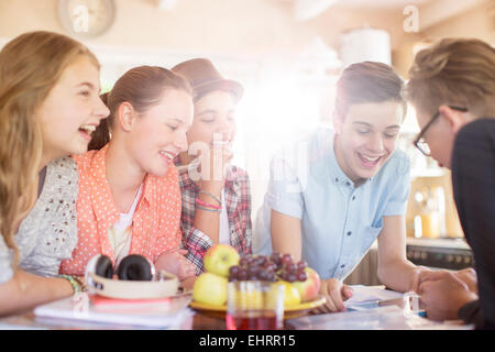 Group of smiling teenagers gathered around table in dining room Stock Photo