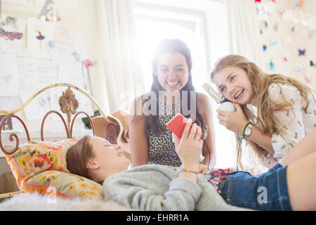 Three teenage girls listening to music from smartphone in bedroom Stock Photo