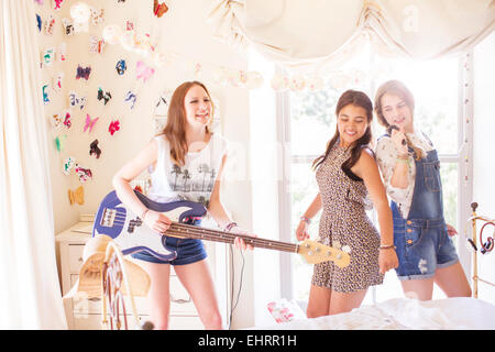 Three teenage girls playing music and singing in bedroom Stock Photo