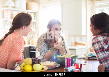 Three teenage girls talking at table in dining room Stock Photo