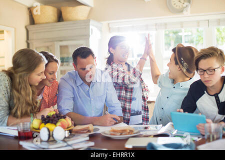 Teenagers with mid adult man sitting at table in dining room Stock Photo