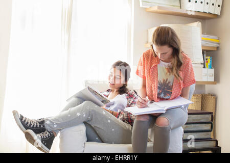 Two teenage girls doing homework in room Stock Photo