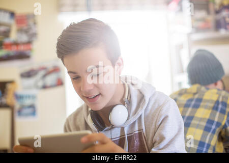 Two teenage boys sitting in room and using electronic devices Stock Photo