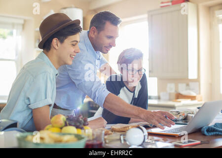 Mid adult man with teenage boys using laptop in kitchen Stock Photo