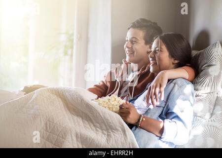 Teenage couple lying in bed and watching tv Stock Photo