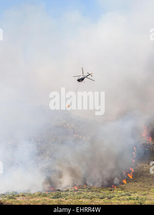 Helicopter drops water over fire in Western Cape, South Africa, on a summer day. Stock Photo