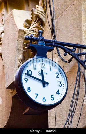 Old round style clock hanging on a wall. Stock Photo