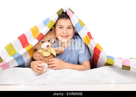 Studio shot of a playful kid holding a teddy bear under a blanket isolated on white background Stock Photo