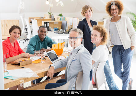 Group portrait of smiling office workers at table Stock Photo