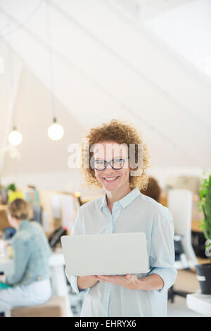 Portrait of woman holding laptop at office Stock Photo