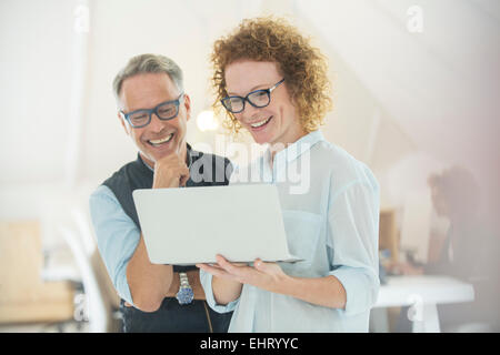 Two smiling office workers using laptop Stock Photo