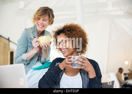 Two office workers talking at desk using laptop Stock Photo