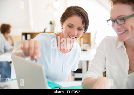 Women using laptop in office and smiling Stock Photo