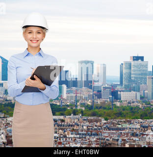 smiling businesswoman in helmet with clipboard Stock Photo